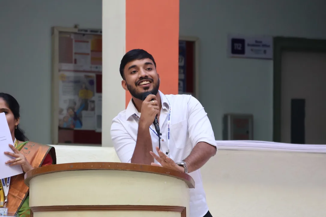 Siram speaking from a college podium